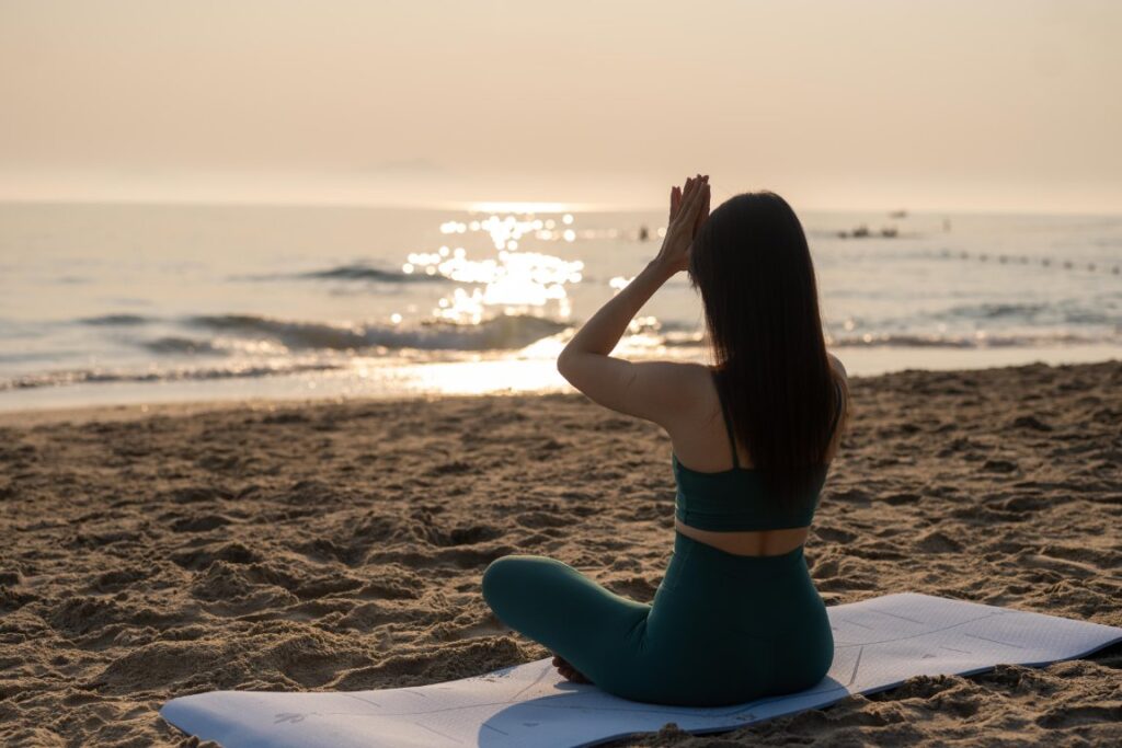 Beach yoga class in progress with students aligned in warrior poses at sunrise.